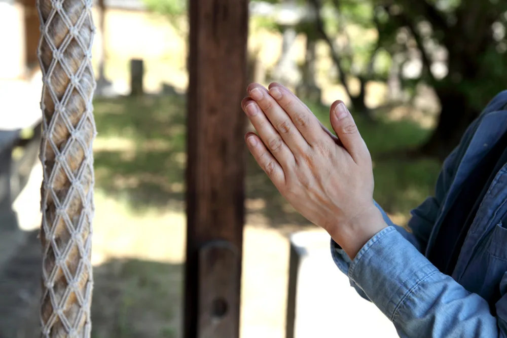 神社で手を合わせている人