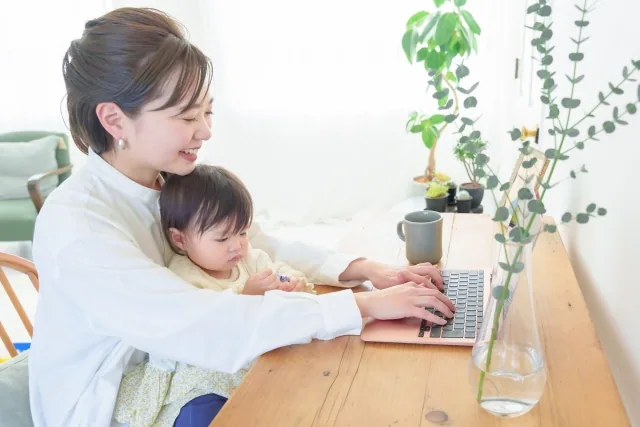 子供と一緒にパソコンで仕事をしている女性