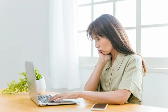 パソコンを触りながら悩んでいる女性