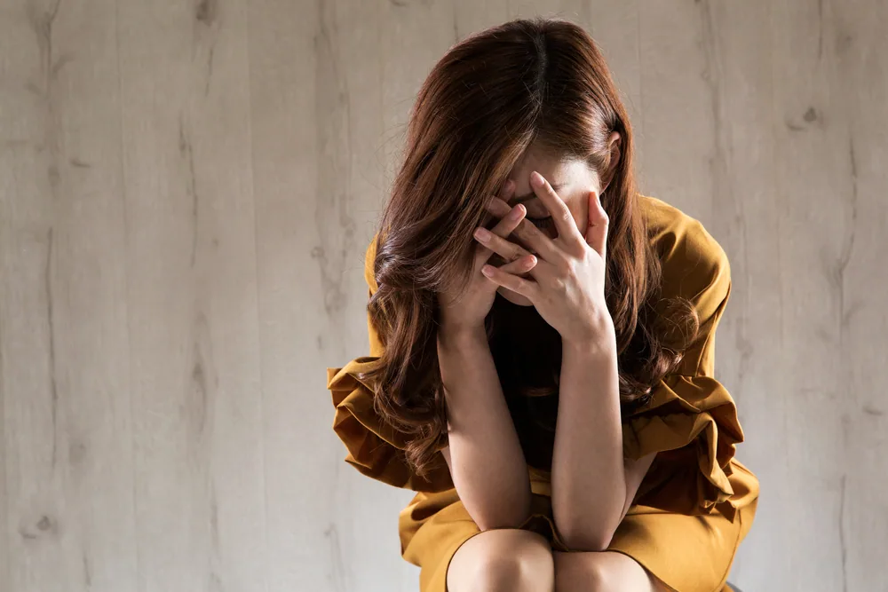 悩んで顔を覆っている女性