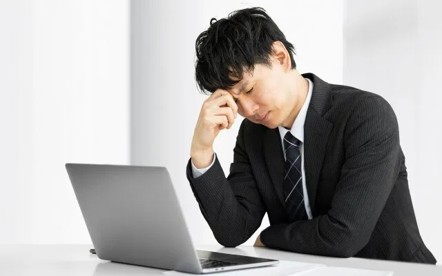パソコンの前で悩んでいる会社員