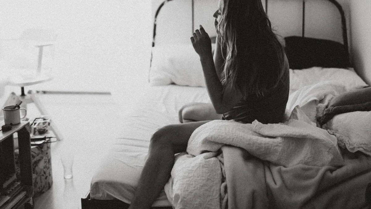 部屋で一人ベッドに座る女性
