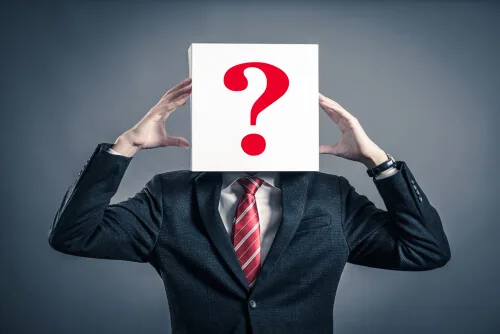 ？を顔に掲げて持っているスーツの男性