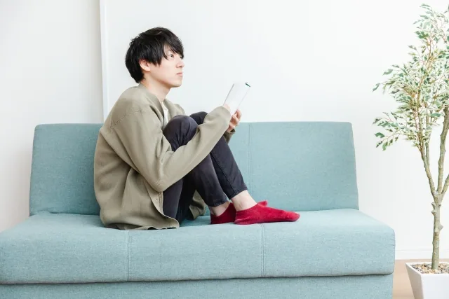 ソファーに座って考えている男性