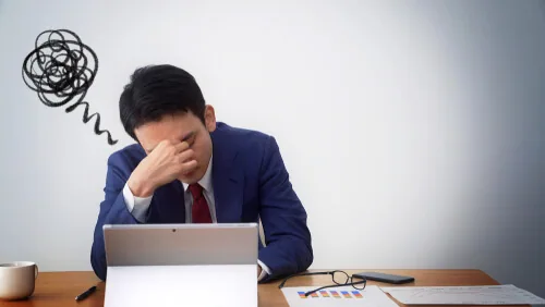 才能がないと悩んでいる机に座っている職場の男性