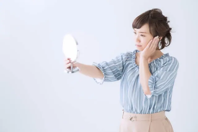 コンプレックスがあり鏡の前で気にしている女性