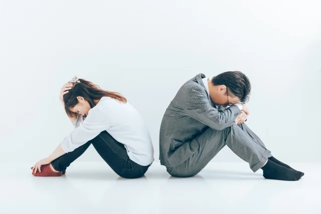 背を向けてうつむいている男女