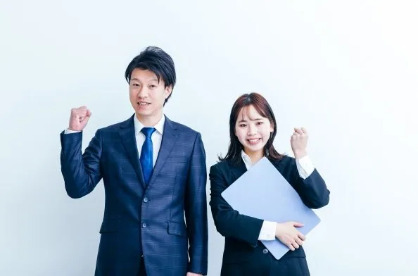 ガッツポーズをしているスーツ姿の男女