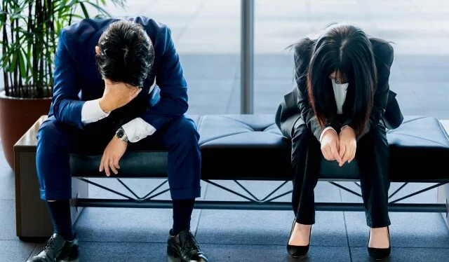 椅子に座って悩んでいる男女