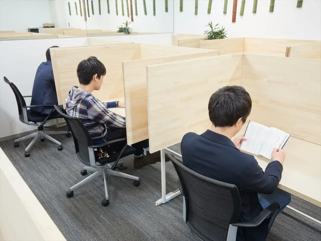 仕切りのある場所で各勉強している男性たち