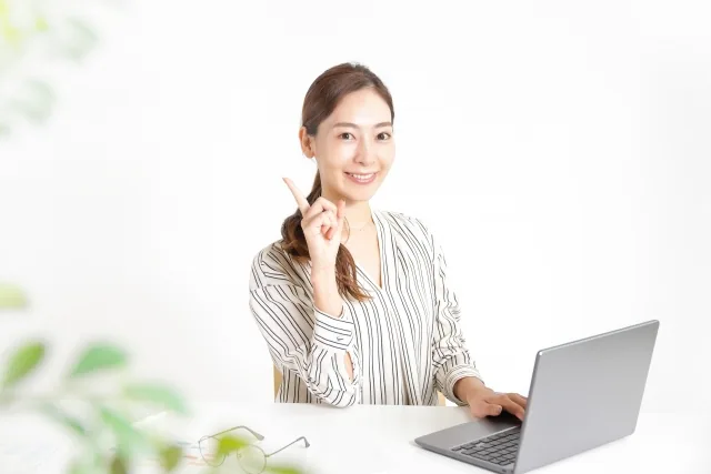 パソコンの前で自信ありげに人差し指を上げている女性