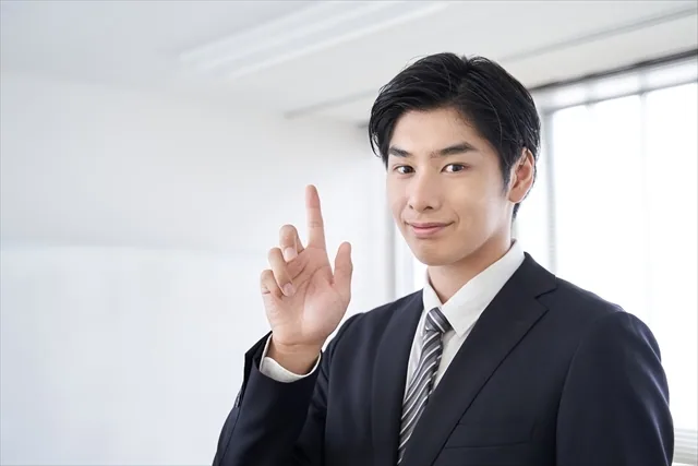 人差し指を上げて自信がありげなスーツ姿の男性