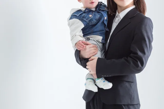 赤ちゃんを抱いているスーツ姿の女性