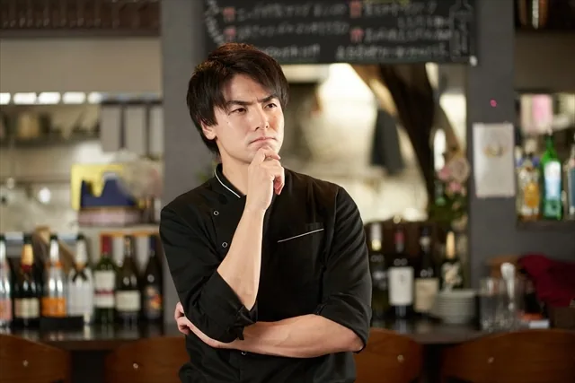 飲食店の制服で考えている男性