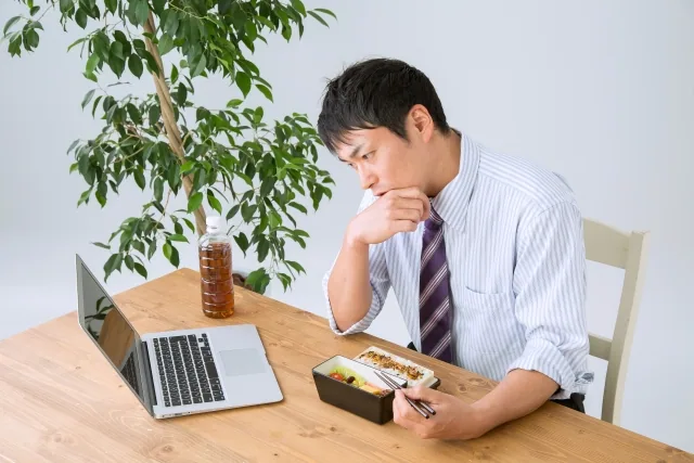 お昼ご飯を食べながらPCしている男性
