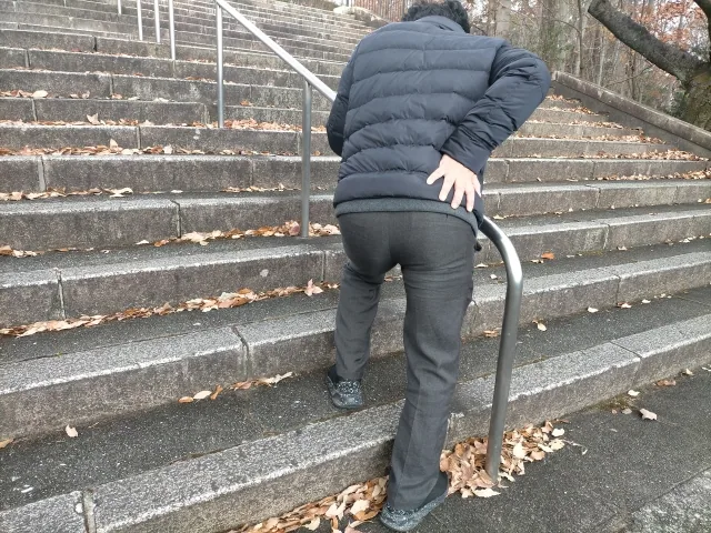 腰に手を添えて苦しそうに立っている男性