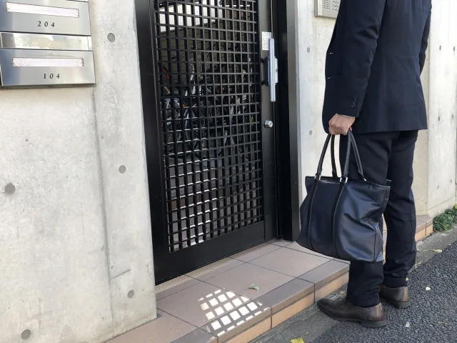 個人宅の前で待っている営業男性