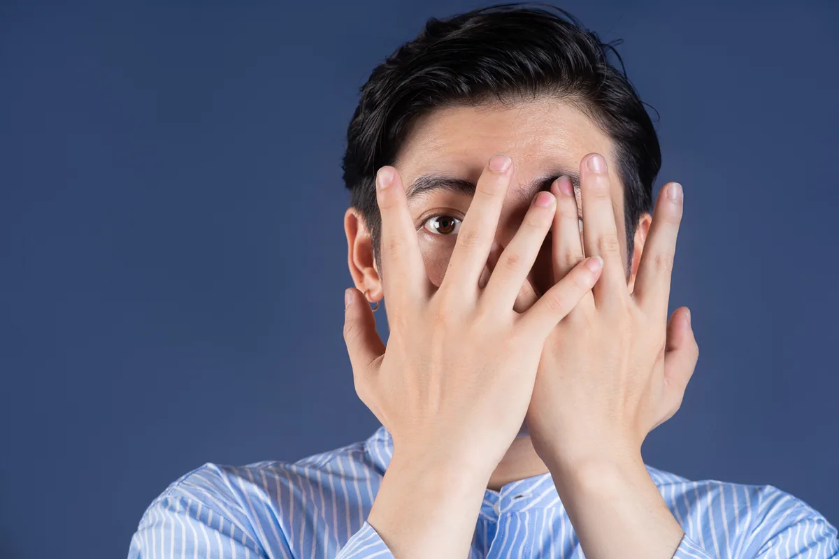 顔を手で隠している男性