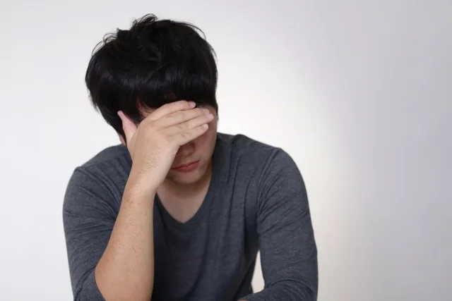 手に顔をあてて悩んでいる男性