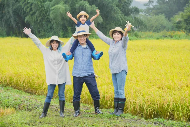 田舎の田んぼで万歳をしている家族