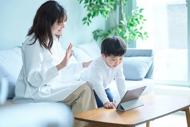 子供がいる状態でパソコンに向かって話しかけている女性