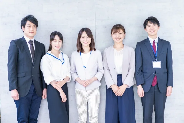 スーツ姿で笑顔で立っている男女