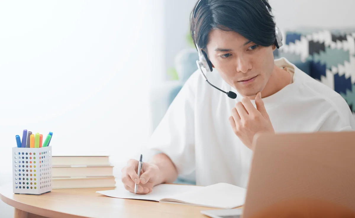 自宅でパソコンとヘッドフォンで勉強をしている男性