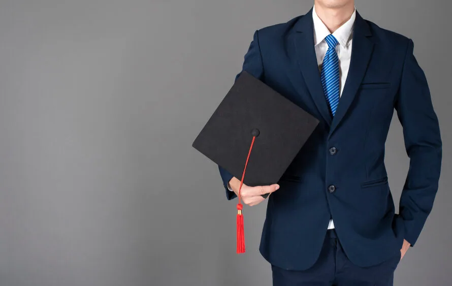 大学卒業の帽子を持ったスーツ姿の男性