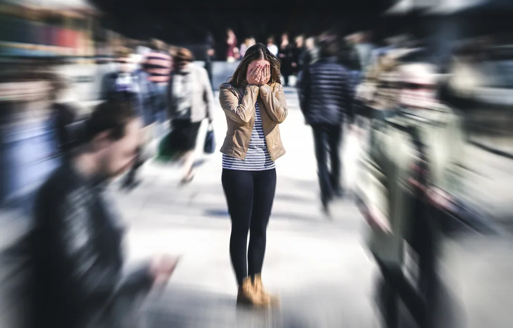 人が多い通りで立ち止まって悩んでいる女性