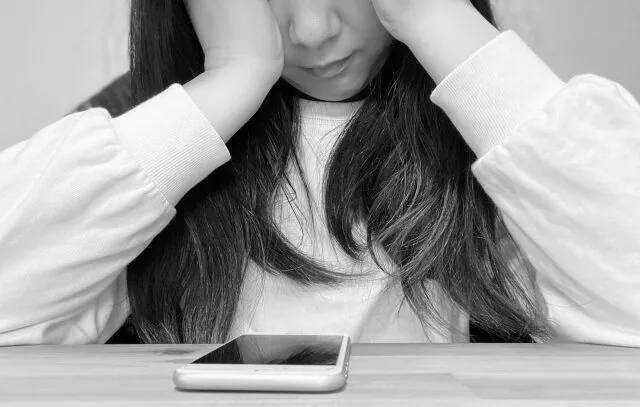 電話を目の前に営業するのを悩んでいる女性