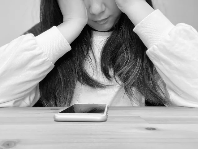 携帯を持って悩んでいる女性