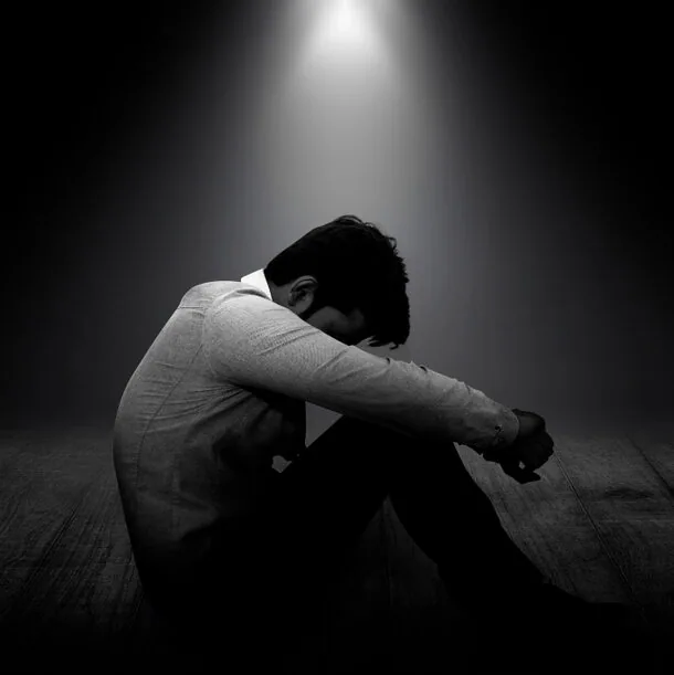 スポットライトに下で悩んでいる男性