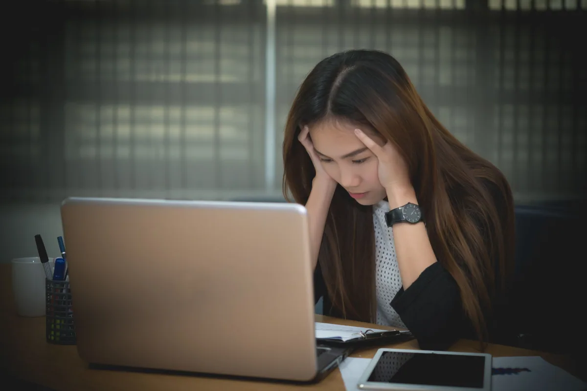 オフィスのパソコンの前で悩んでいる女性