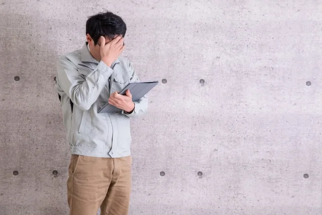 作業服を着て悩んでいる男性