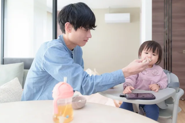 小さな娘にご飯をあげている父親