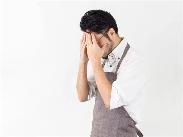 顔を覆って悩んでいる男性