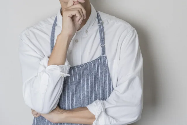 エプロン姿の男性が考えている様子