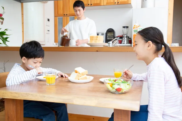 子供のご飯を用意している父親と２人の子供