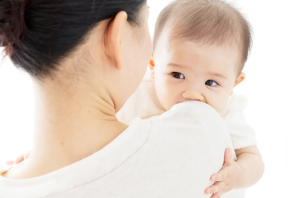 母親の肩に抱かれている赤ちゃん
