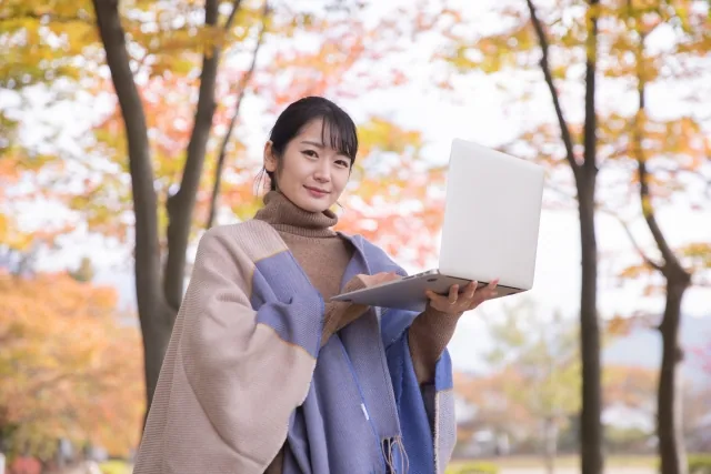 自然の中でパソコンを持っている女性