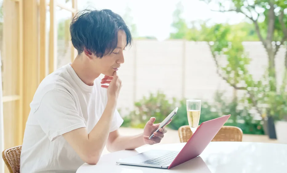 朝庭が見える場所でパソコンで作業をしている男性