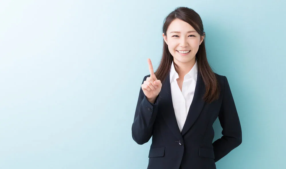 人差し指を上にあげている笑顔の女性