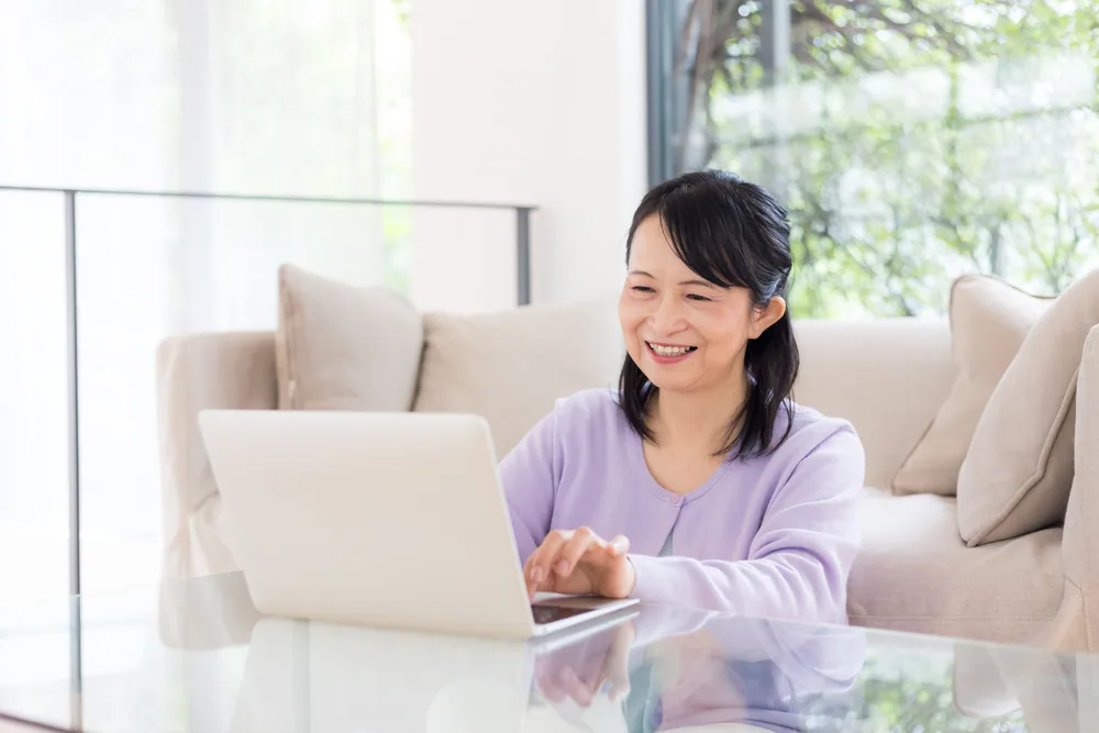 笑顔でパソコンに向かって作業をしている女性