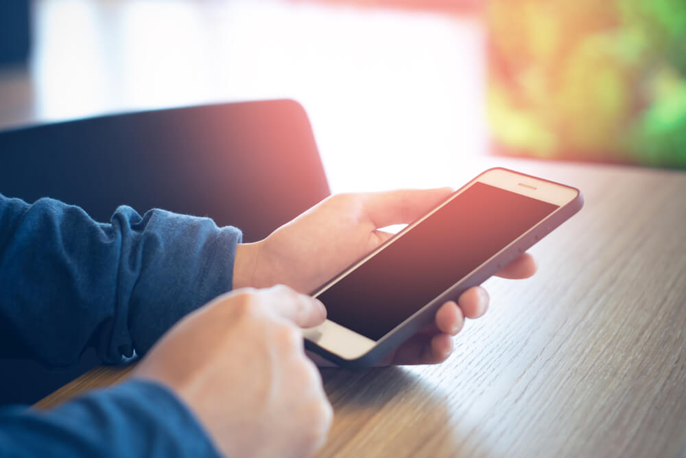 昔の友人に連絡をしようとしている携帯電話と手の様子
