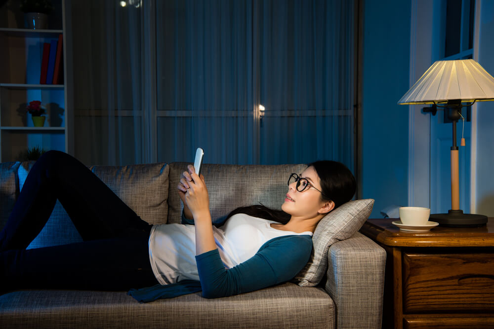 本を読みながらソファーに横たわっている女性