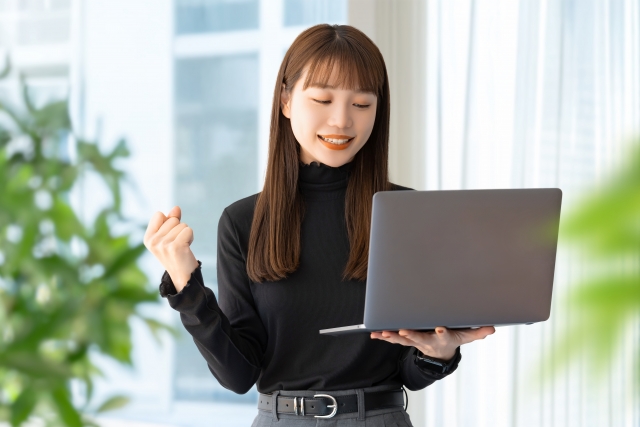 パソコンを持ってガッツポーズしている女性