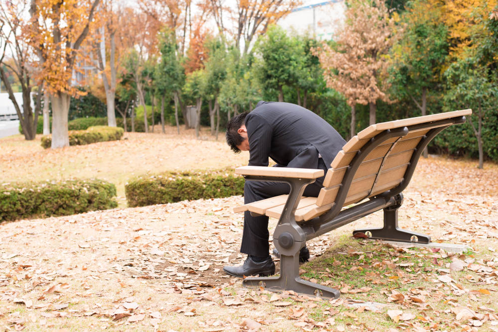 ベンチに座って悩んでいる男性