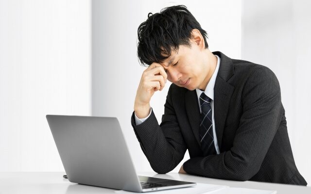 パソコンの前で悩んでいる会社員