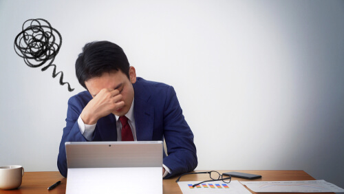 才能がないと悩んでいる机に座っている職場の男性