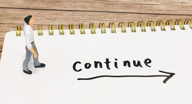 コンティニューと書かれた文字の横を歩く男性